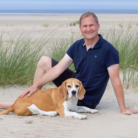 Thore Scheu mit Beagle Fotograf Thore Scheu sitzt mit einem Beagle im Dünensand auf Norderney